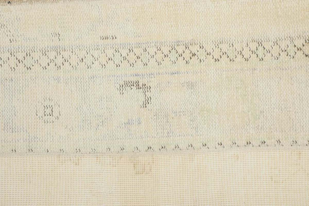 View of the low wool pile and a subtle pattern on an ivory patch of the rug