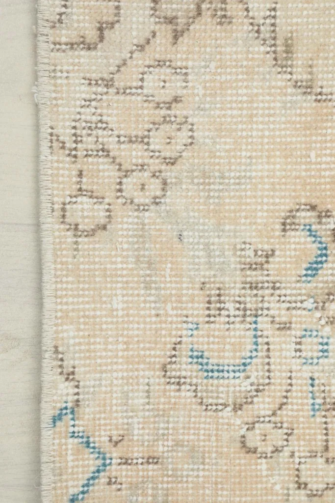 Detail of the rug's edge, showing the blend of colors and the hand-knotted construction.