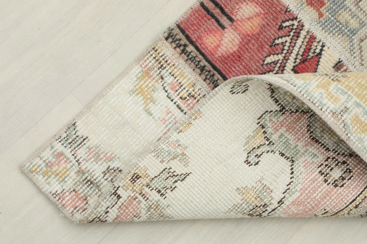 Corner of the Faded Patchwork Geometric Runner lifted, showing the cotton foundation and hand-knotted weave