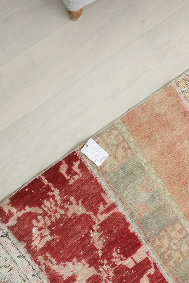 Detail of a red distressed patch and a beige geometric section on the runner, with a product tag visible