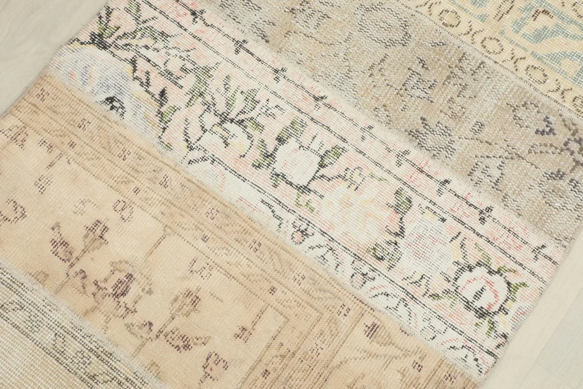 Close-up of different patchwork panels, revealing faded rose, green, and blue accents within the patterns