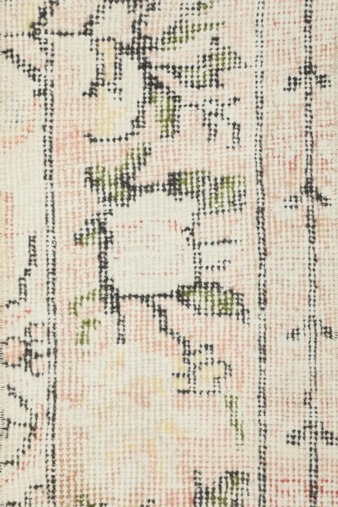 Texture detail of the low wool pile, showing the hand-knotted construction and distressed patterns
