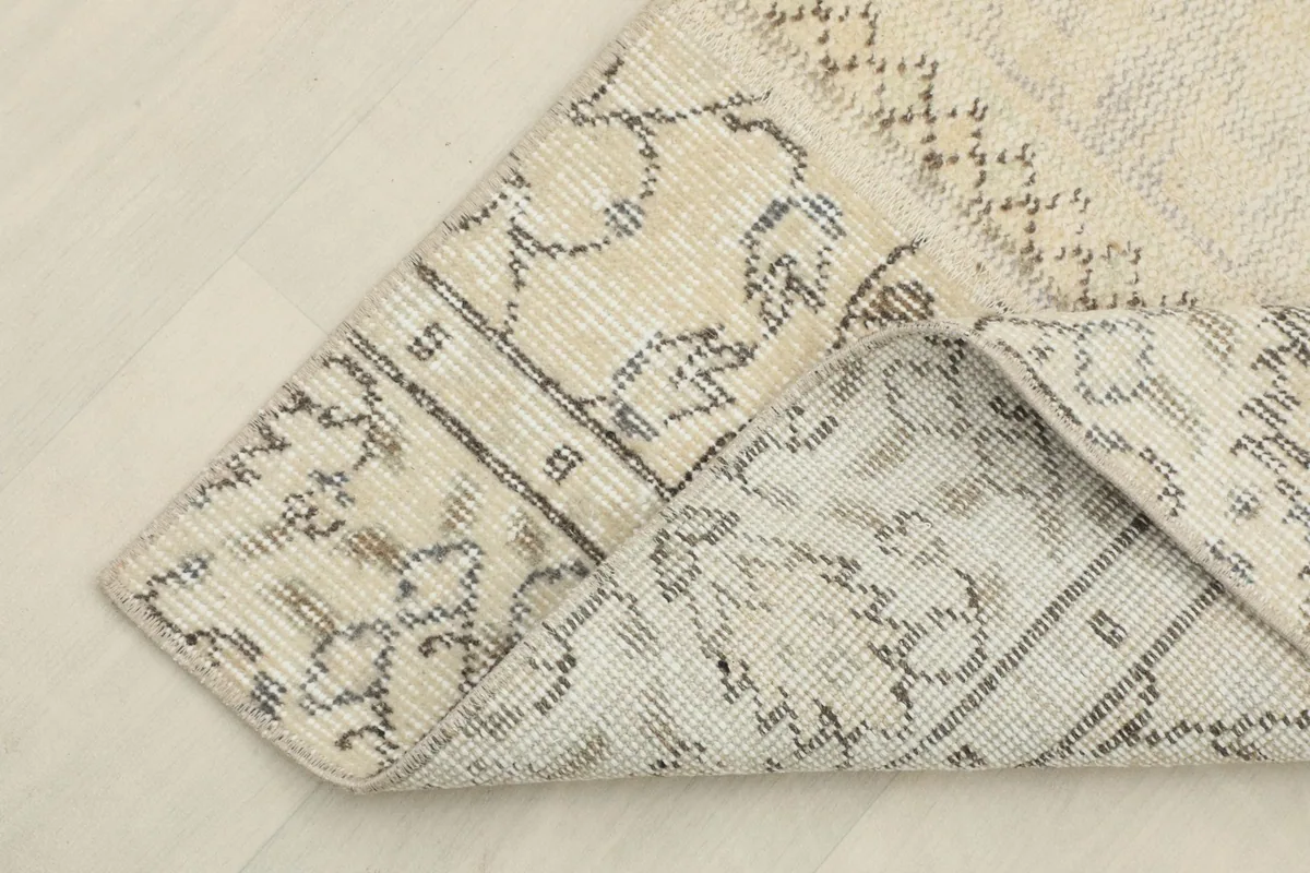 Corner of the rug folded back to reveal the cotton foundation and reverse side of the hand-knotted construction