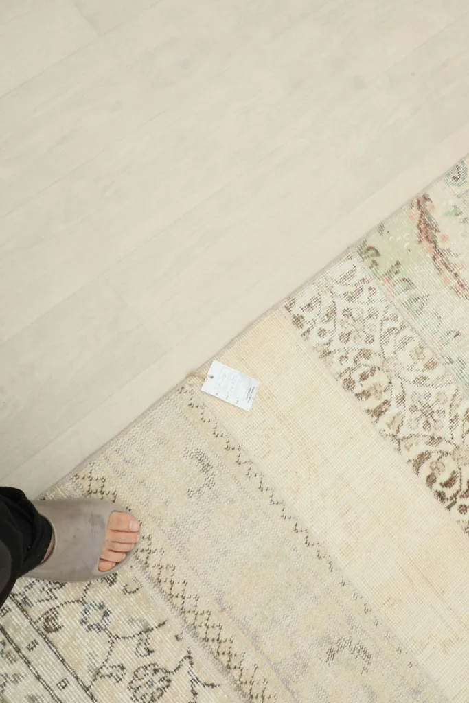 View of a foot next to the rug, providing a sense of scale and showing the rug's texture on the floor