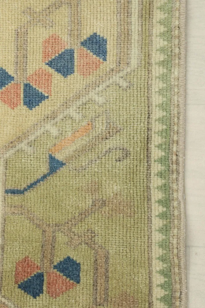 Close-up of the low wool pile and a green border with small geometric patterns