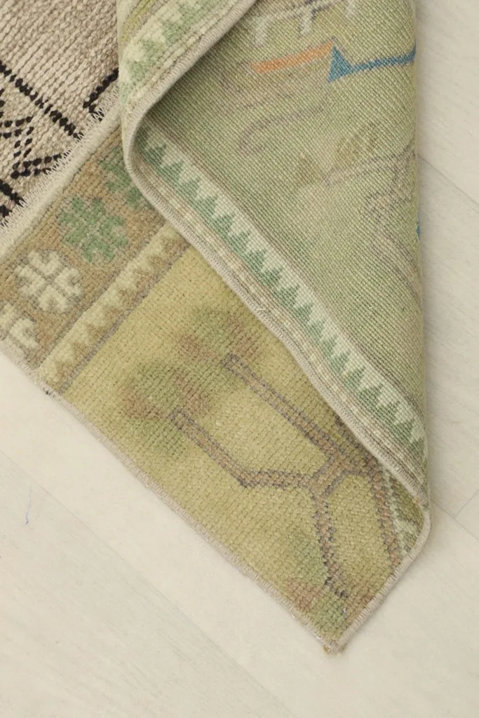 View of the rug's backside, showing the hand-knotted cotton foundation and a folded corner