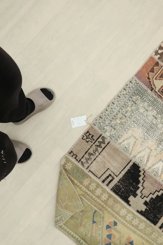 Overhead view of a person's feet next to the runner rug, showing scale and texture