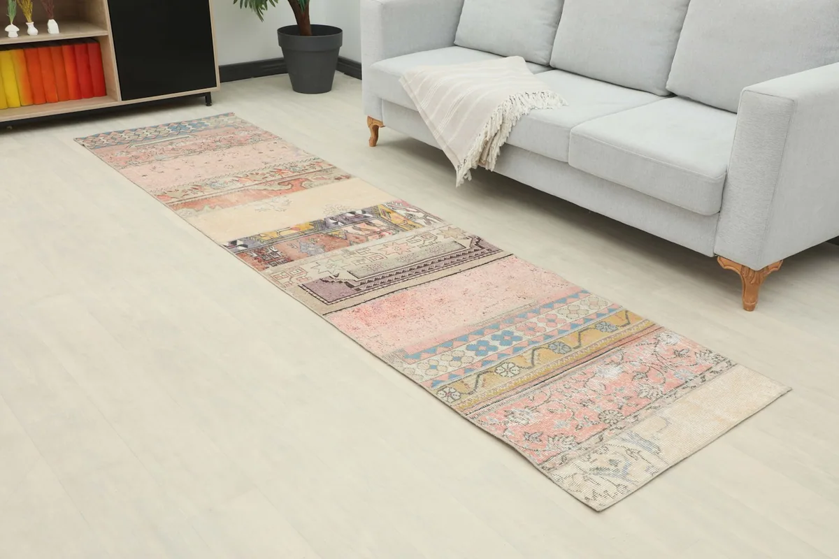 Angled view of the vintage runner rug extending from a sofa, highlighting its various geometric and floral sections