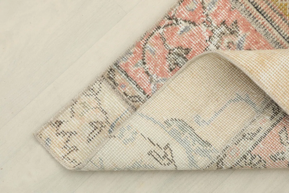 Corner of the runner rug folded back, showing the wool pile and cotton foundation texture