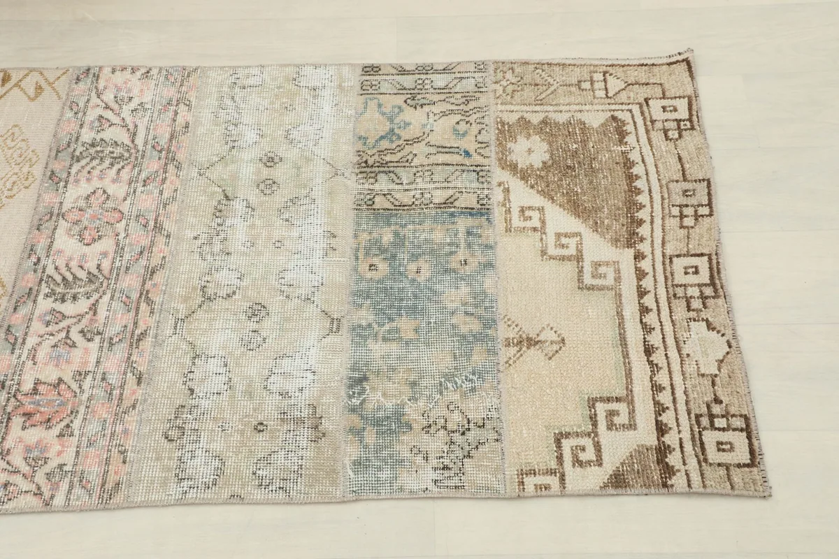 Close-up of one end of the rug, showing beige, blue, and brown patchwork sections with tribal motifs