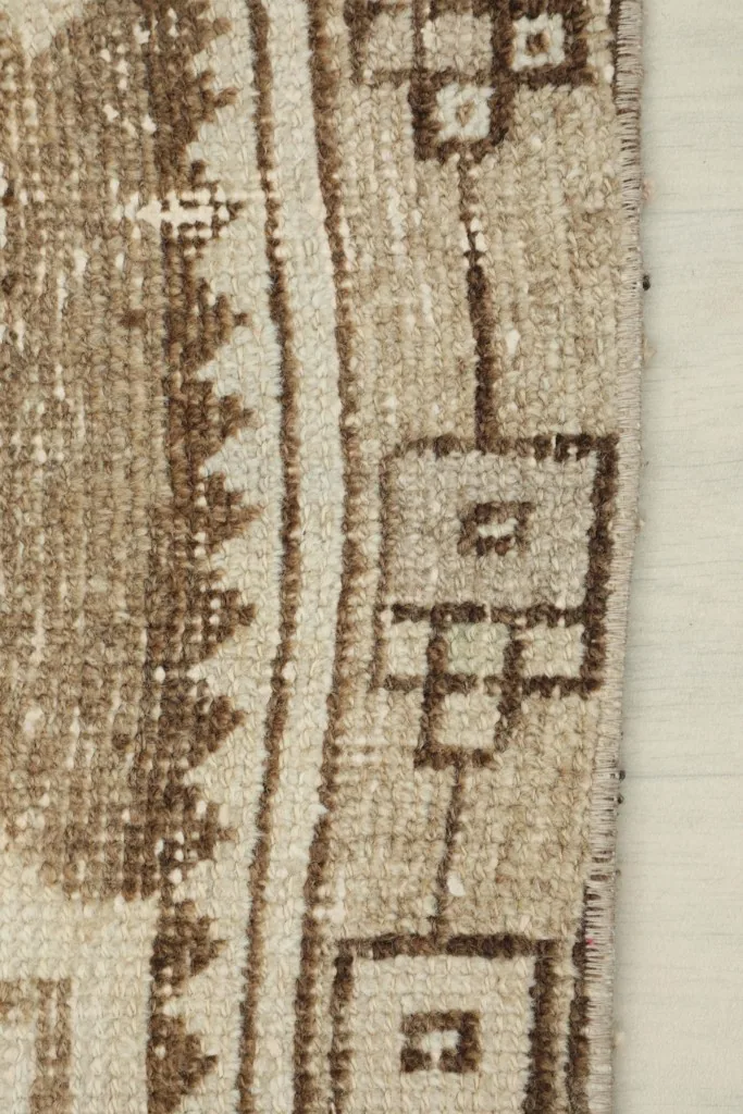 Detail of a brown and beige section with tribal patterns and a low pile texture