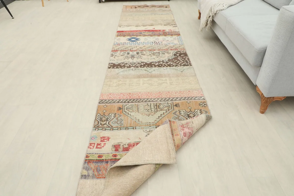 Runner rug partially unrolled in a room, showcasing its length and patchwork design.