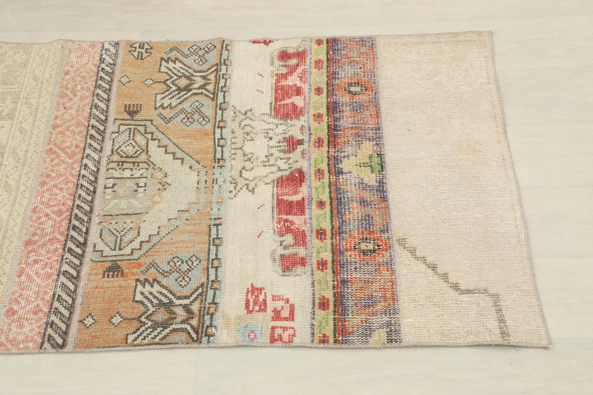 Close-up of a section of the runner, showing beige, rust, red, and purple patches with geometric designs.