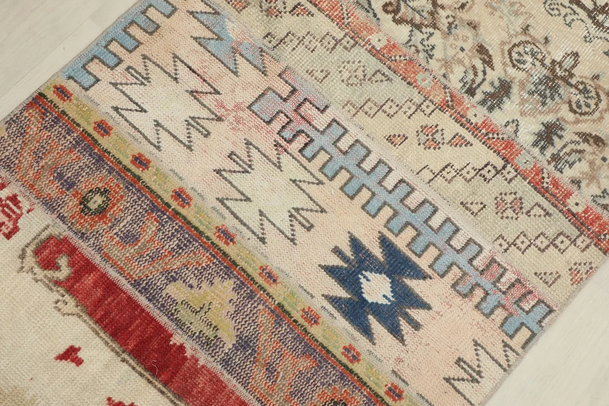 Close-up of the rug's central section, revealing blue, red, and ivory geometric and tribal motifs.
