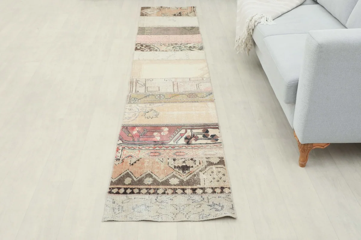 Full view of the vintage patchwork runner rug laid out in a room, seen from a higher angle.