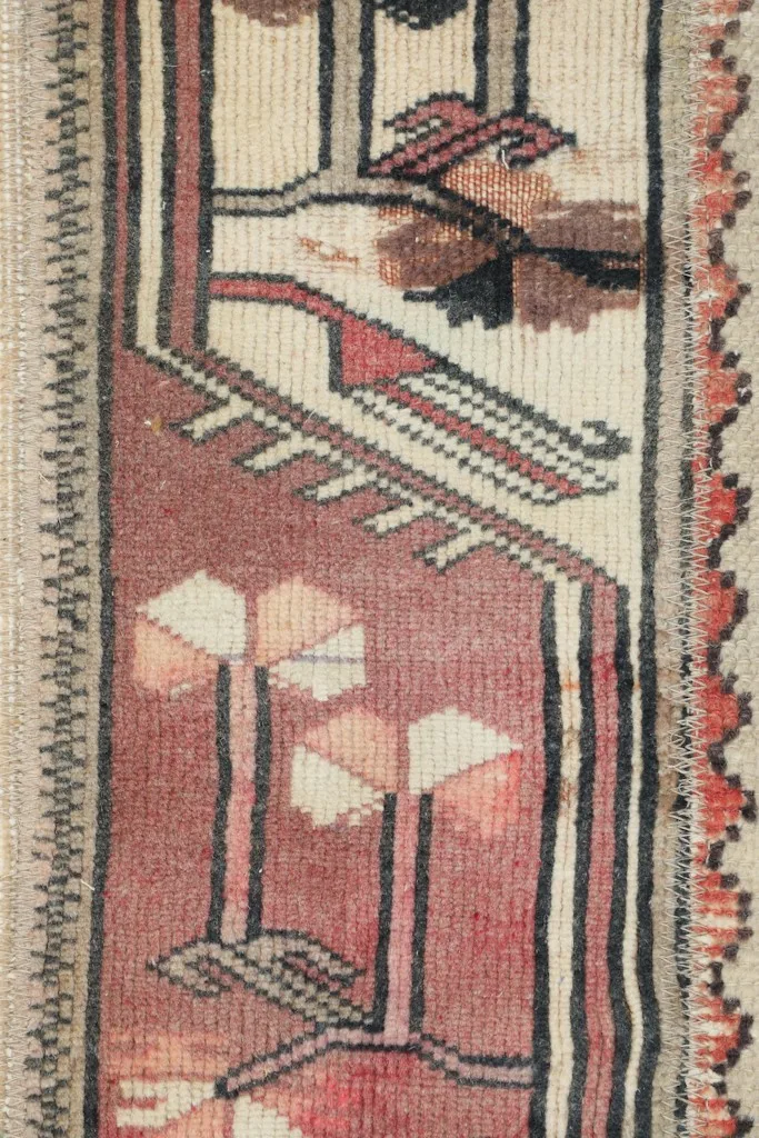 Close-up of a rose and cream patterned patch with tribal motifs in the runner rug.