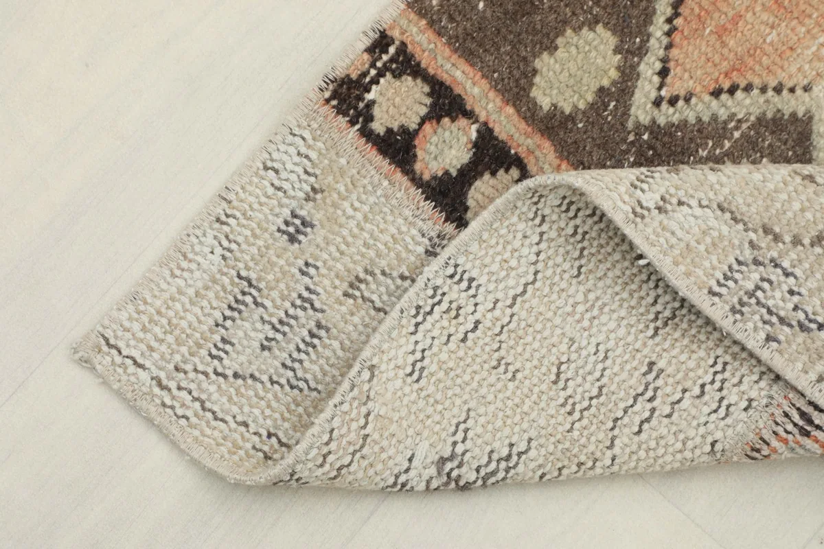 View of the low wool pile and backing of the vintage hand-knotted runner rug, folded to show thickness.