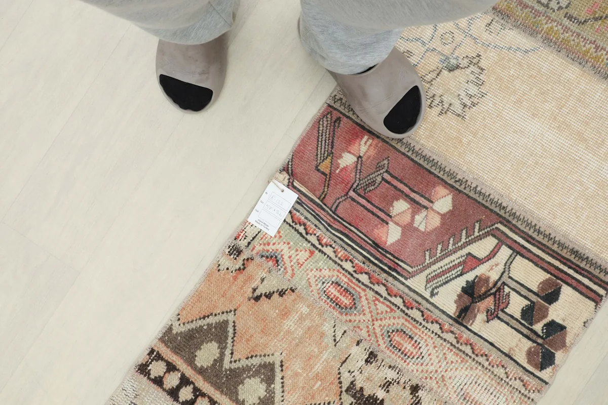 Overhead view of a person's feet next to a section of the patchwork runner rug, showing scale.