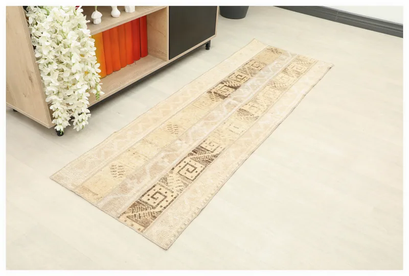 Full top view of a tan and brown geometric striped vintage runner rug on a white background.