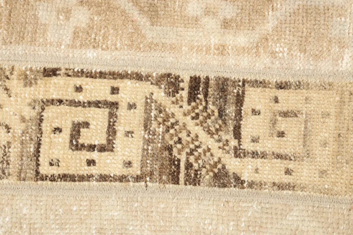 Extreme close-up of a brown geometric spiral motif within a tan stripe.