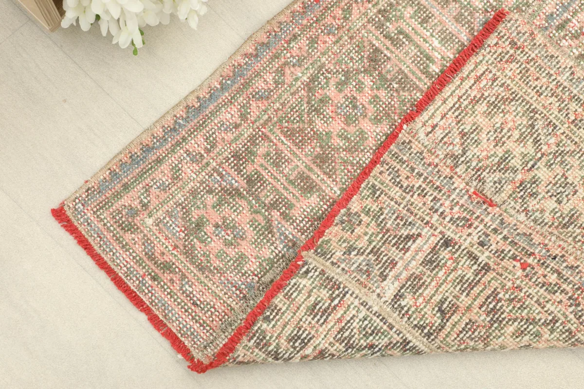 Corner of the rug folded to show the cotton foundation and the reverse side of the hand-knotted construction.