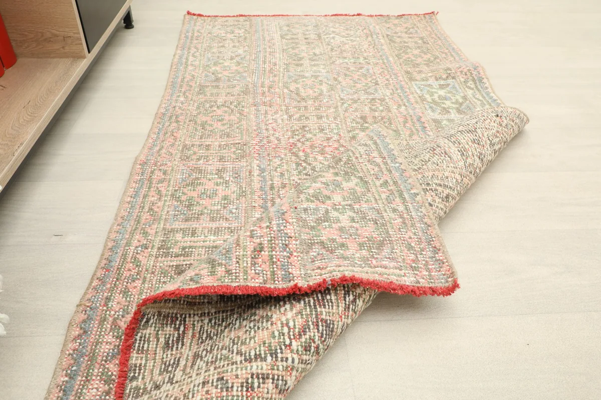 Rug partially folded, illustrating its flexibility and the thickness of the wool pile.