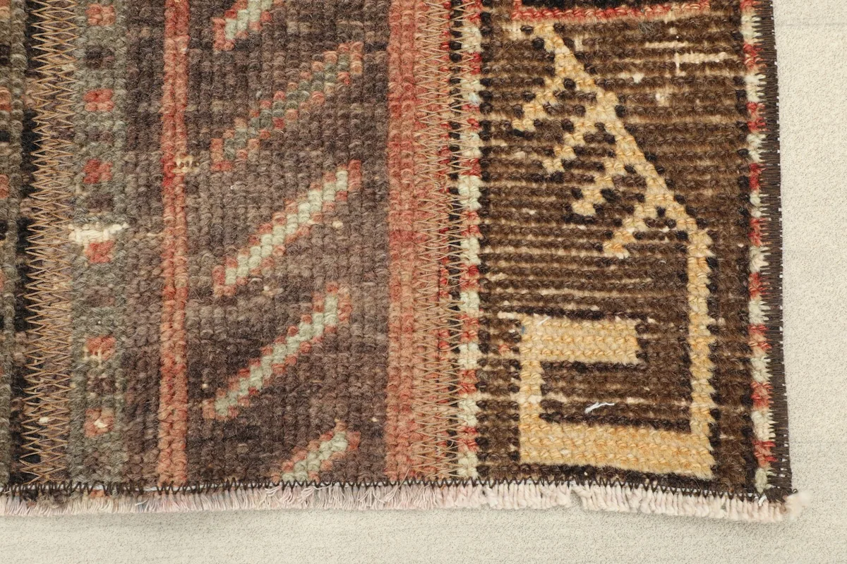 Close-up detail of the rug's texture and brown, rust, and beige color variations.