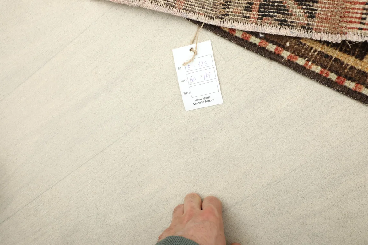A person's foot next to the rug, indicating its mini size and scale.