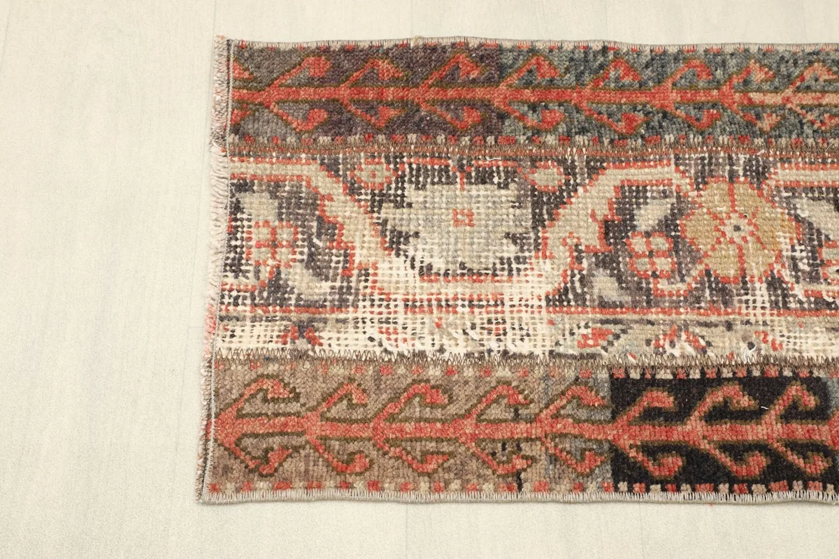 Angled view highlighting the varied geometric patterns and color transitions across one end of the rug.