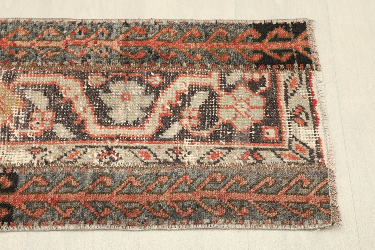 Angled view showing the intricate tribal motifs and the low pile texture from the other end of the rug.