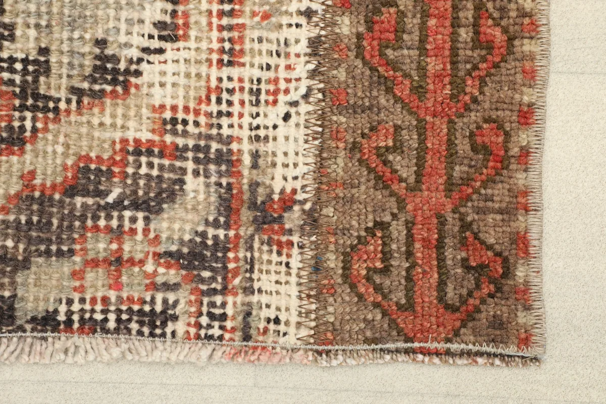 Close-up detail of the rug's surface, showing the faded rust and brown tones, and visible wear in the pile.