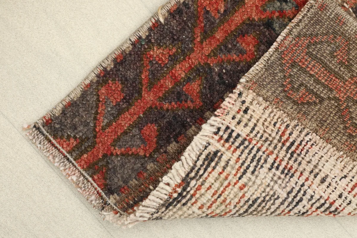 View of the rug's back and edge, showing the cotton foundation and the tightly woven structure.