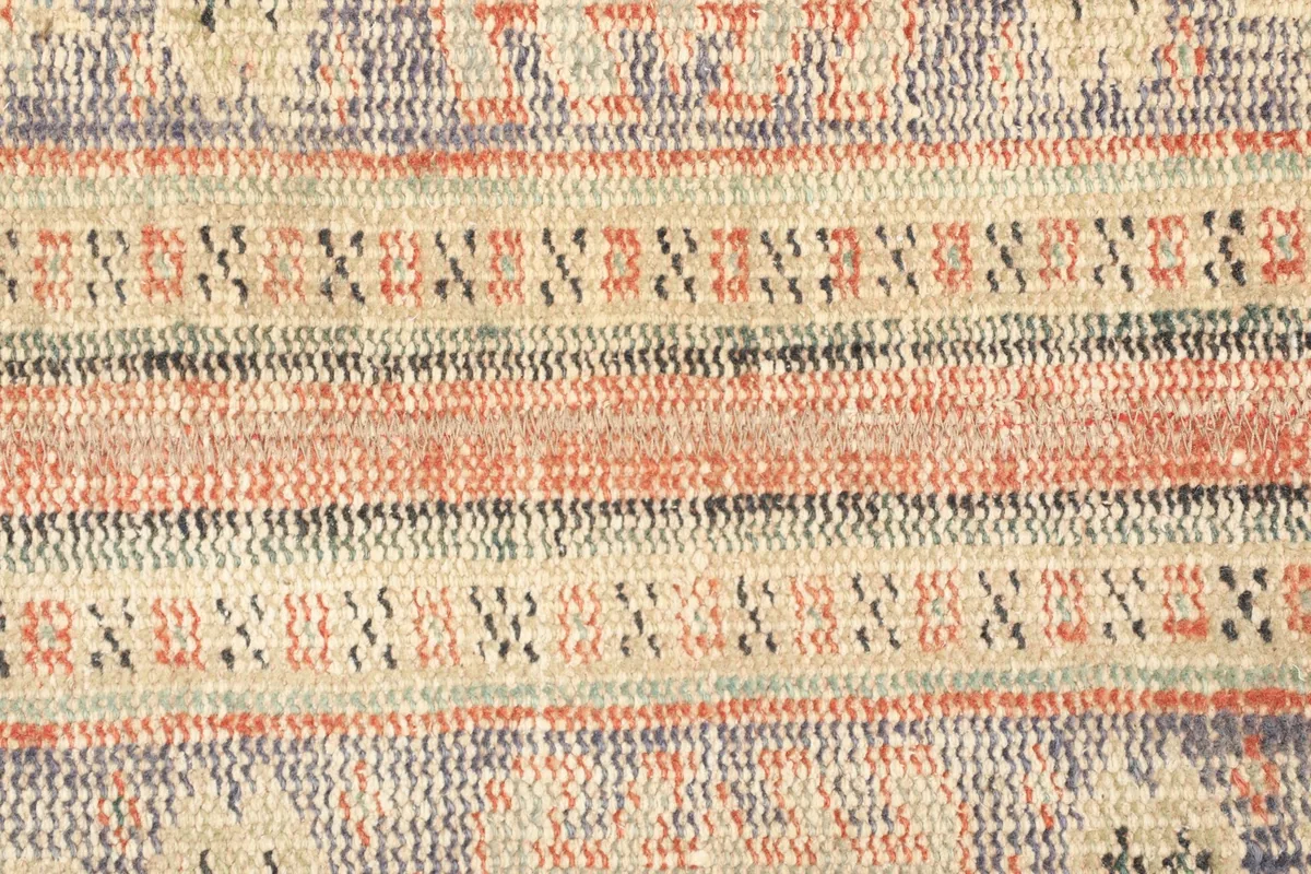 Detailed view of the intricate geometric motifs and striped bands within the rug's design.