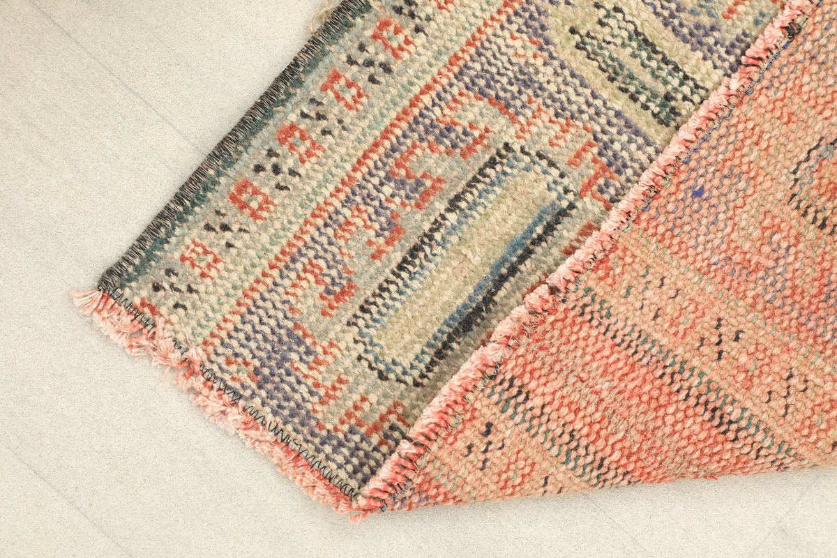 Corner of the rug folded to reveal the thickness of the hand-knotted wool pile and cotton foundation.