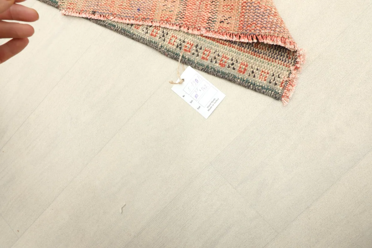 A hand and product tag visible next to the folded rug, indicating its authenticity and quality.