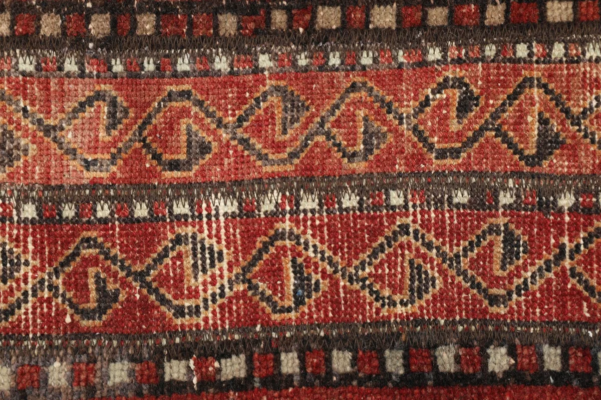 Detailed view of the intricate tribal patterns and texture of the vintage rug.