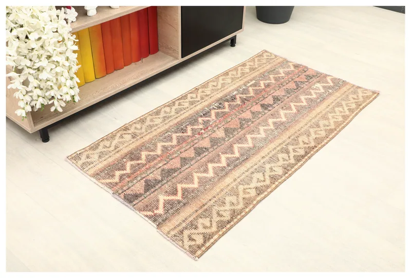 Full top view of the beige and rose tribal geometric rug on a white background.