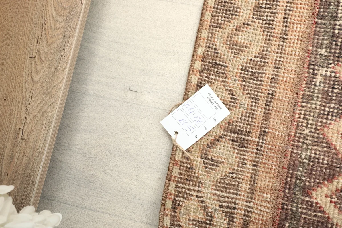 Detail shot of the rug's corner with a product tag, showing the texture on the floor.