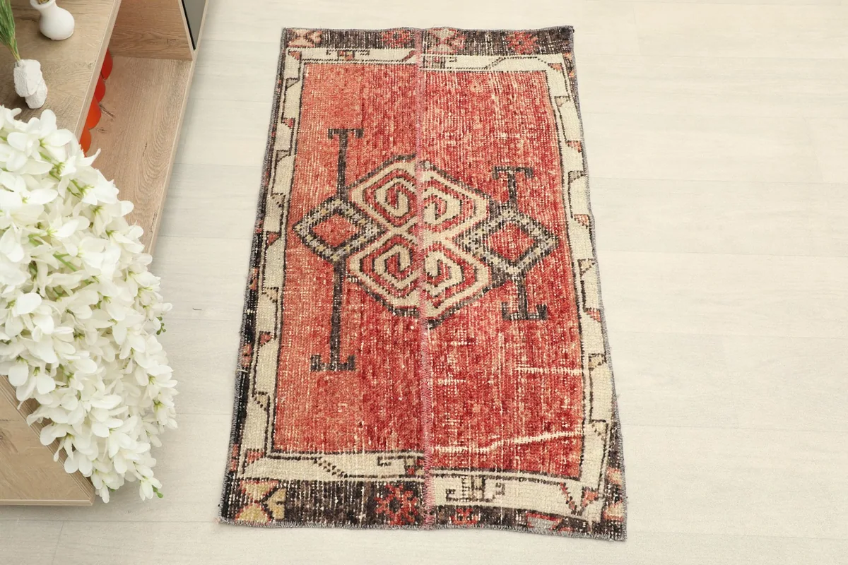 Top-down view of the red vintage hand-knotted rug showing its central tribal design.