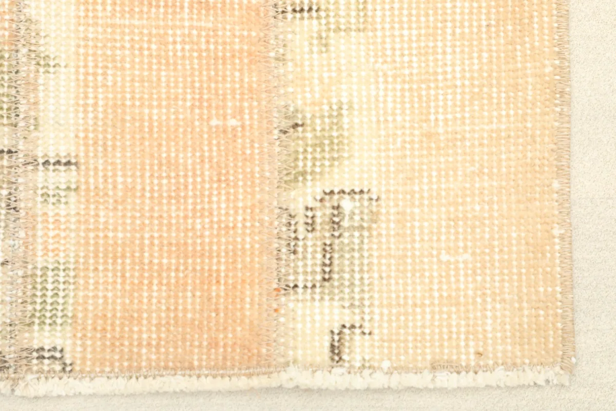 Close-up detail of the rug's texture and color variations, showing beige, rust, and green tones