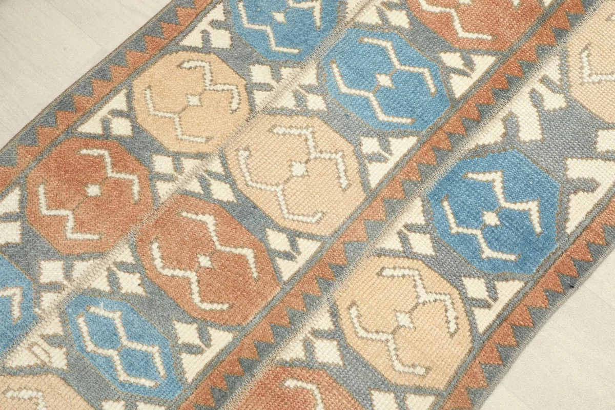 Angled view highlighting the repeating oval motifs and the rust border of the vintage rug