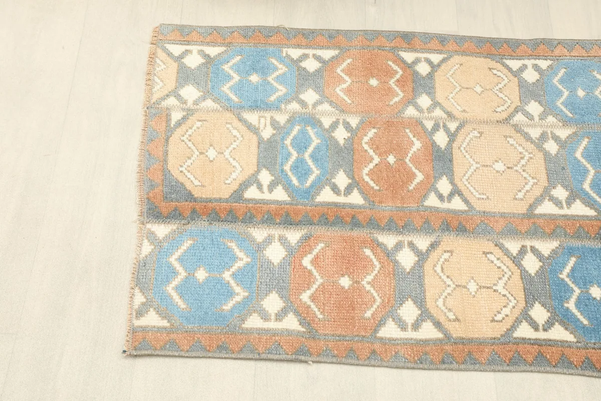 Angled view showing the left side of the gray, blue, rust, and tan area rug