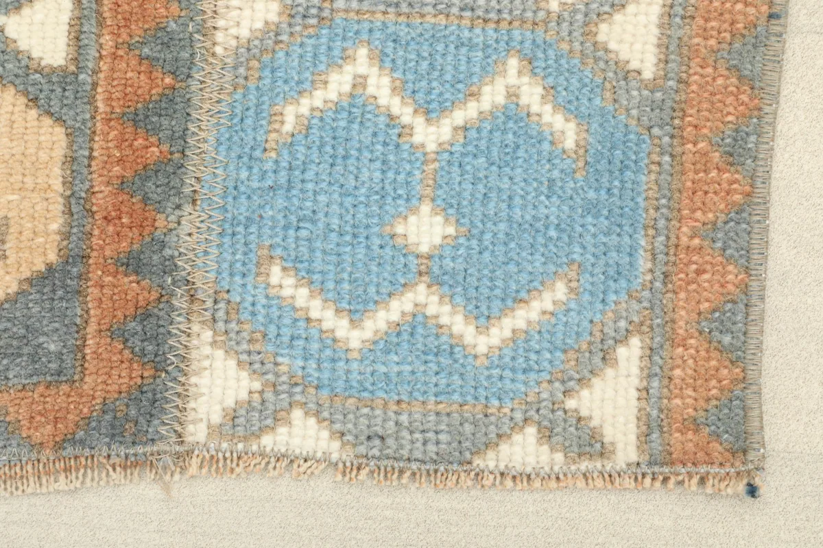 Detailed view of a blue geometric motif and the subtle fringe on the vintage rug