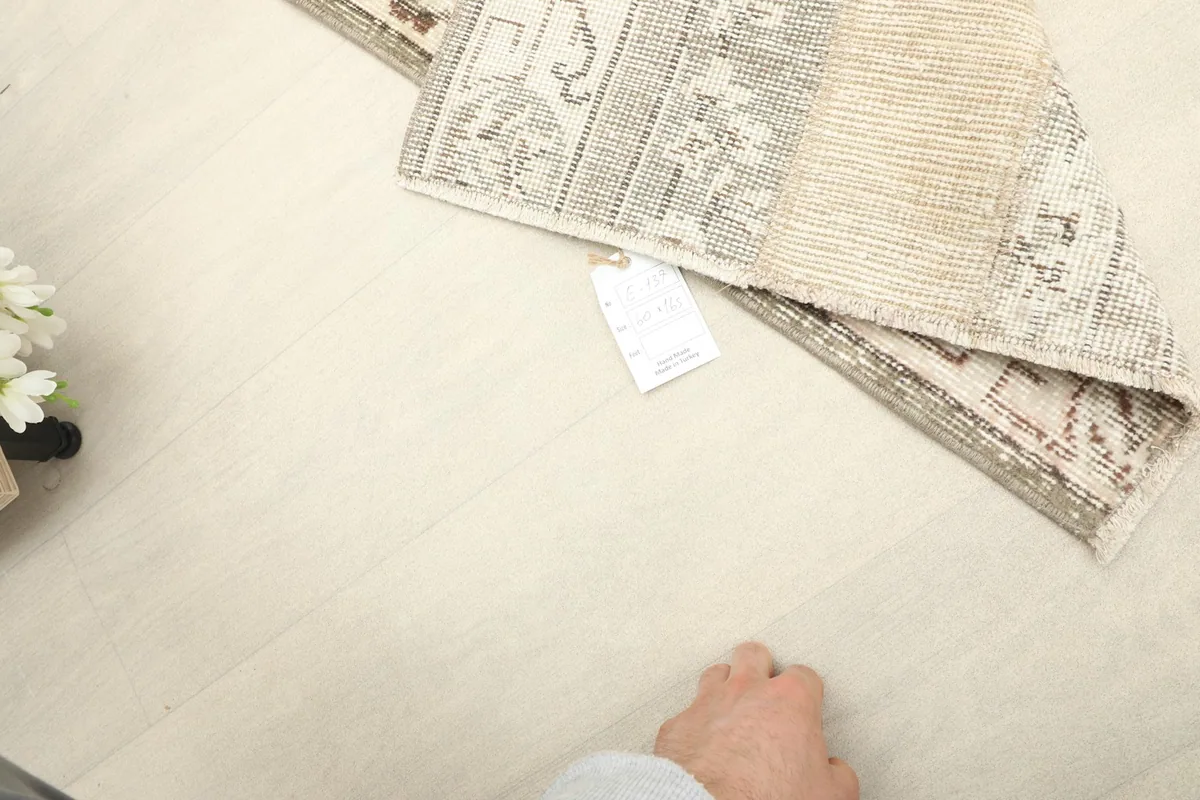 A hand next to the folded rug, providing a sense of scale for the runner's thickness and texture.