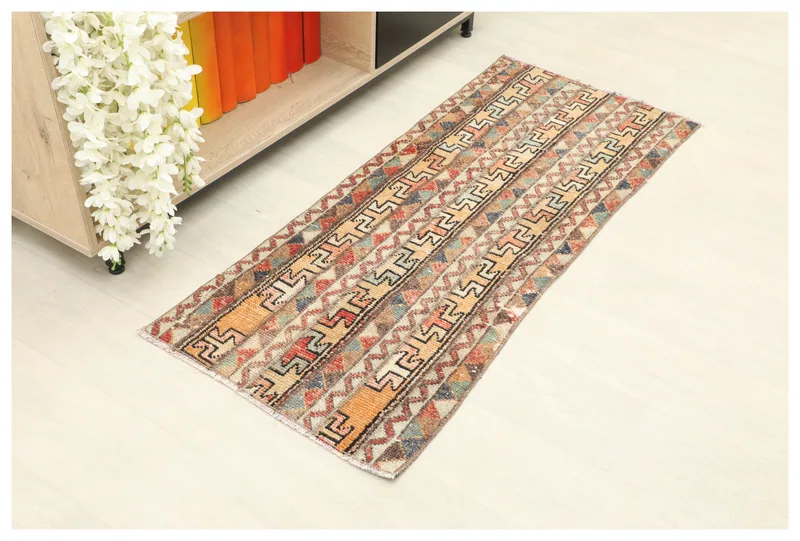 Full top view of the 1'8" x 4'4" orange and beige tribal runner rug on a white background.