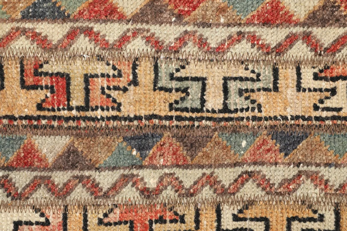 Detailed view of the intricate tribal patterns and colors, including hints of blue and brown.