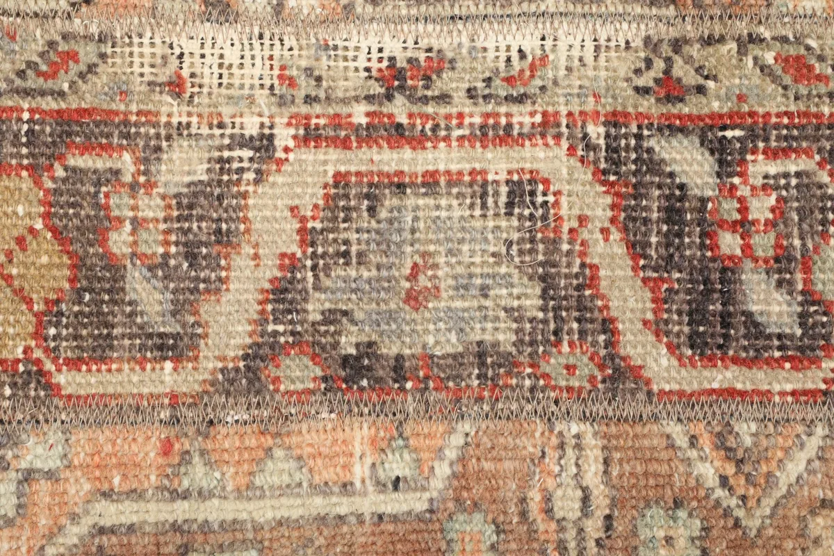 Detailed view of the low pile and intricate tribal motifs in gray, black, and rust