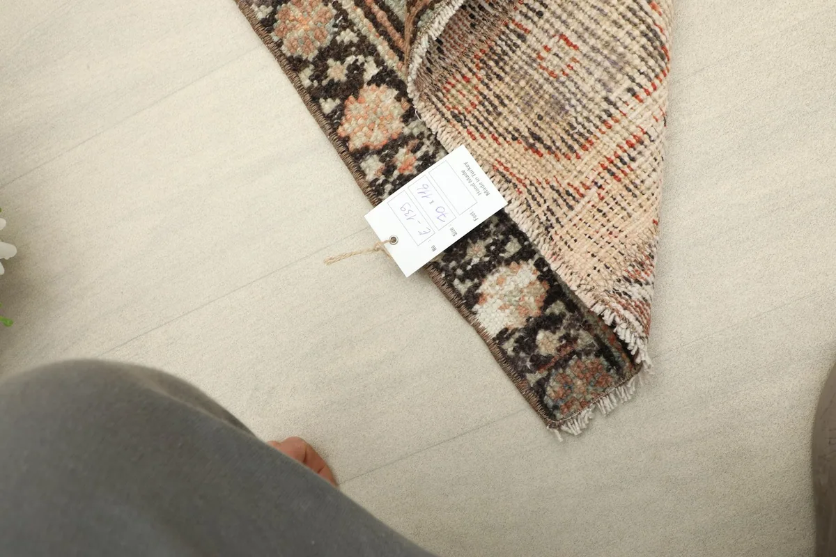 View of the rug's reverse side and hand-knotted craftsmanship with a product tag