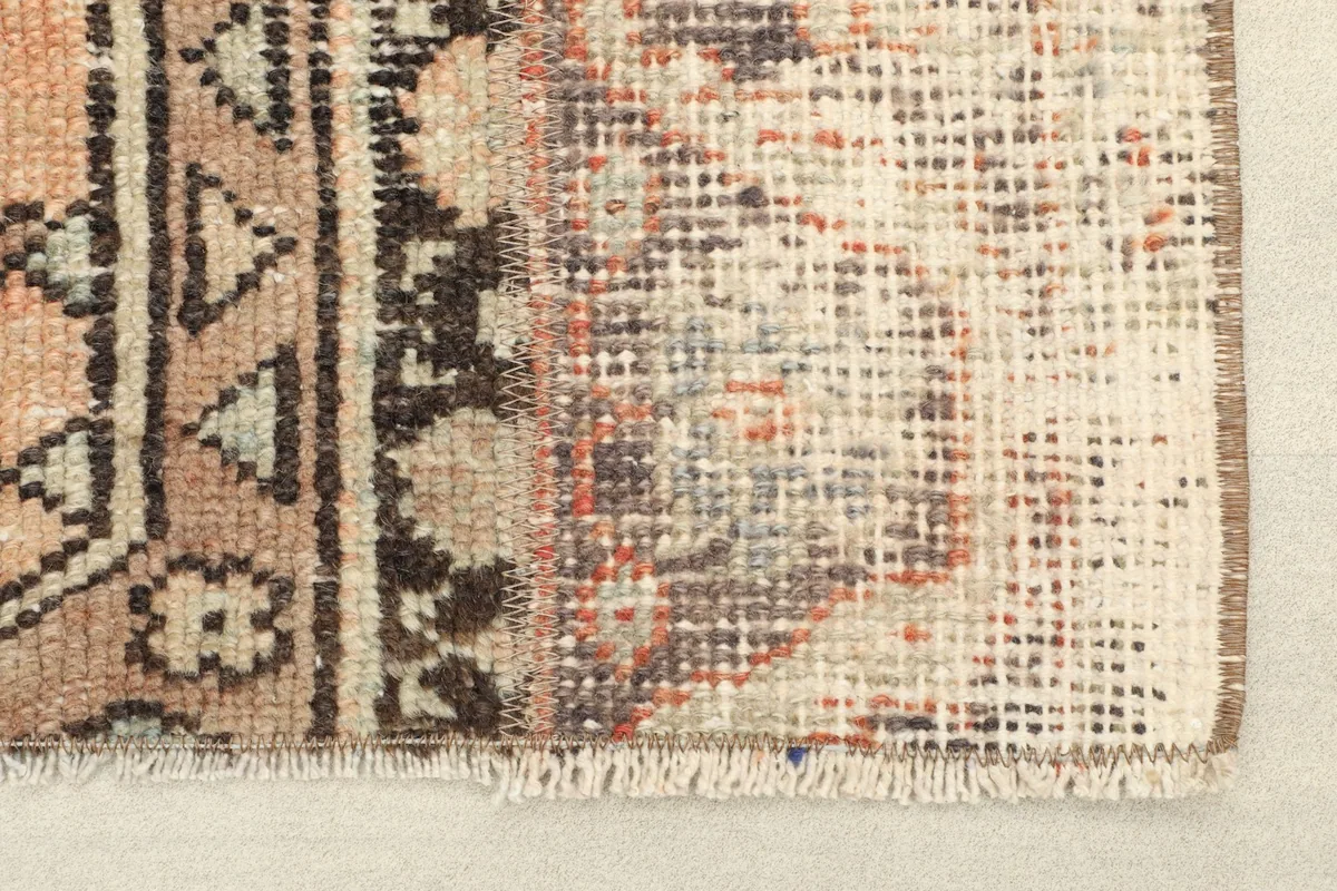 Close-up of the short fringe and distressed edge of the vintage area rug