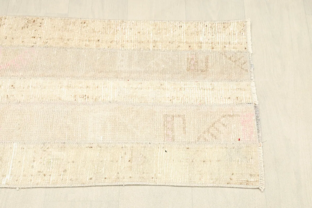 Opposite corner view of the beige rug, illustrating its rectangular shape and finished edges